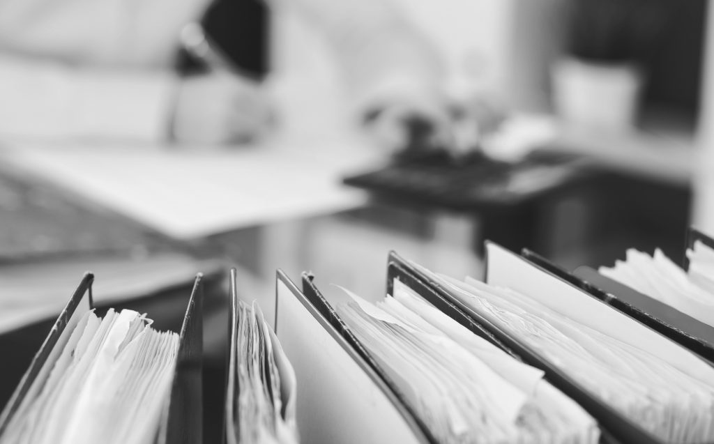 Binders of papers waiting to process by bookkeeper woman or financial inspector, close-up. Business portrait. Audit or tax concepts